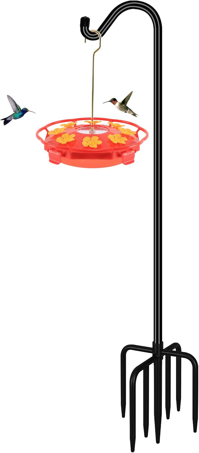 Hummingbird feeder hanging from a shepherd hook in a garden bed